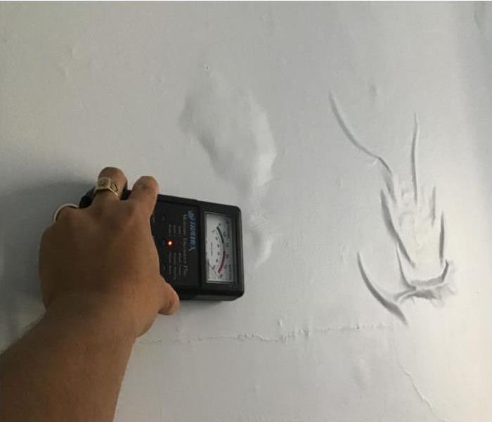 moisture meter over water bubbles under paint on wall 