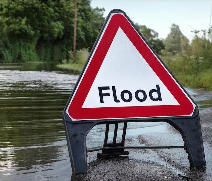 a street completely submerged in water and a flood warning sign in roadway