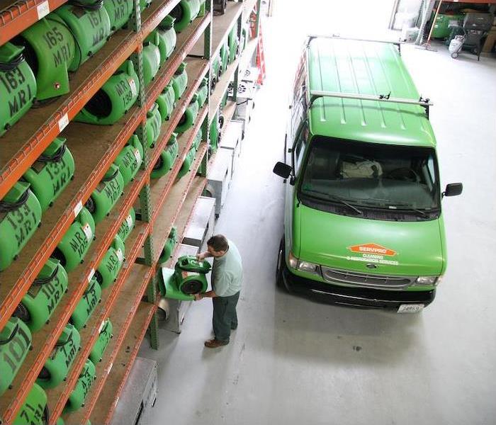 a green SERVPRO van parked in a warehouse full of equipment