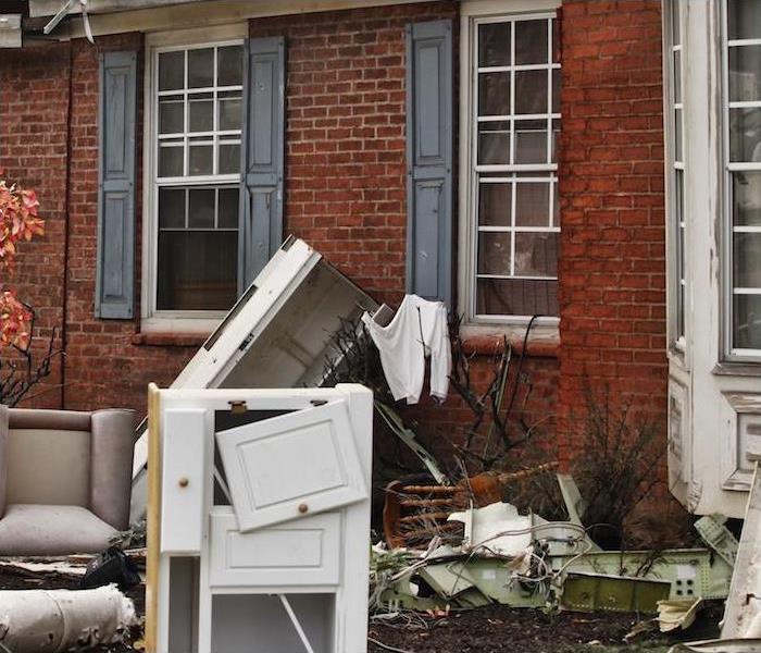 damaged furniture and other home items sitting outside of red brick house