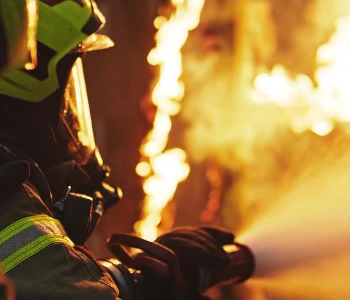 a firefighter battling a fire with a water hose in hand