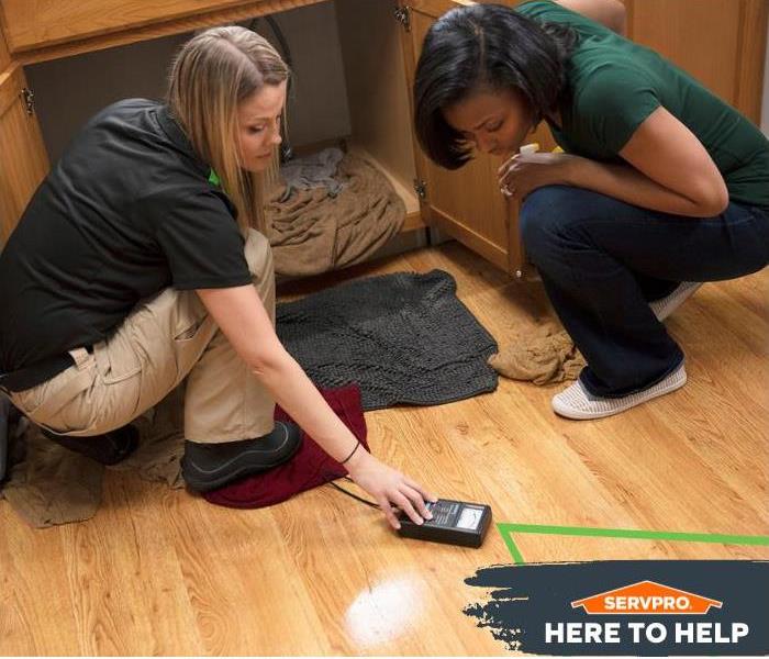 SERVPRO technician showing a homeowner a moisture meter in a water damaged kitchen